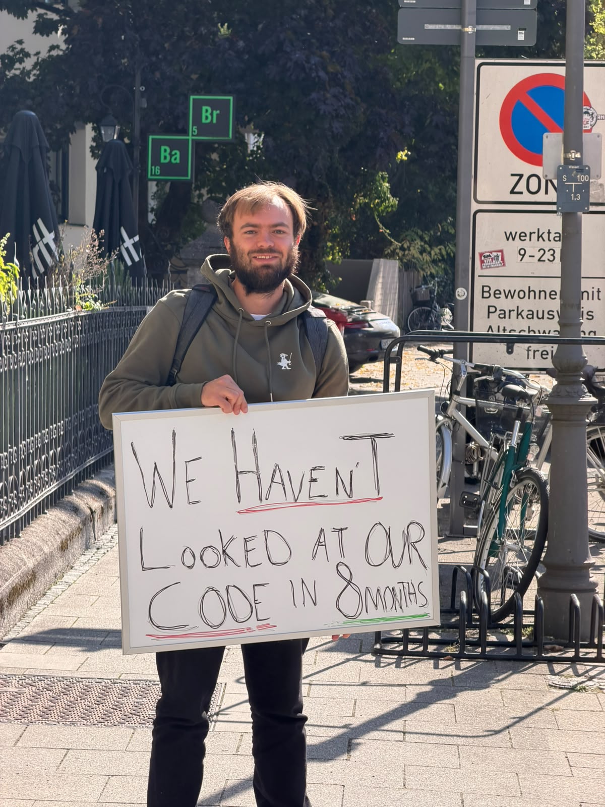 Eivind in the olive crow hoodie, holding the whiteboard on the street.